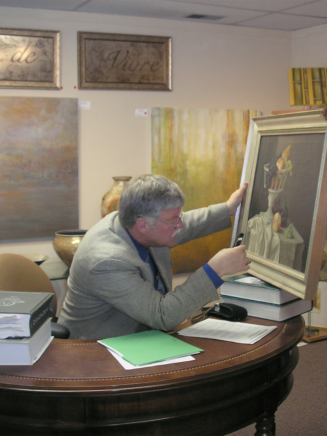 Broadway Galleries guest appraiser inspecting a painting